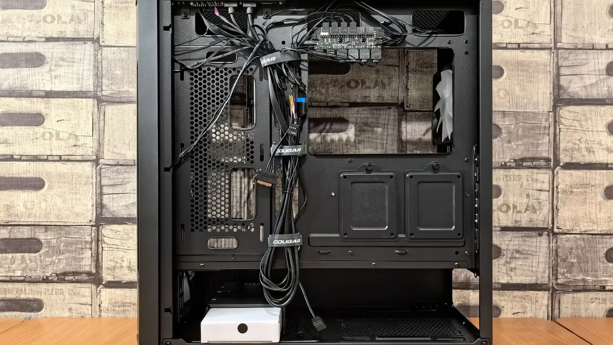 The back of a PC case with power and front-panel cables routed along channels and held down by velcro straps